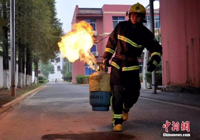 A fireman takes a burning fuel tank away from a residential area. [Photo: Chinanews.com]