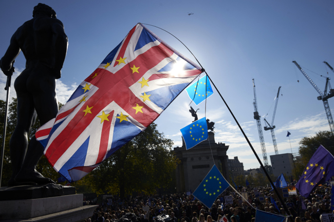 Demonstrators wave a Union flag and European Union flags as they take part in a march calling for a People's Vote on the final Brexit deal, in central London on October 20, 2018. [Photo: AFP]