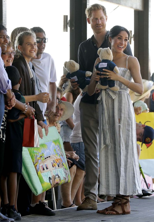Britain's Prince Harry, second from right, and Meghan, Duchess of Sussex receive gifts from the crowd as they walk along Kingfisher Bay Jetty during a visit to Fraser Island, Australia, Monday, Oct. 22, 2018. Prince Harry and his wife Meghan are on day seven of their 16-day tour of Australia and the South Pacific. [Photo: AP]