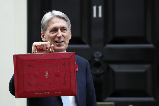 Britain's Chancellor of the Exchequer Philip Hammond poses for the media as he holds up the traditional red dispatch box, outside his official residence 11 Downing Street before delivering his annual budget speech to Parliament in London, Monday, Oct. 29, 2018.[Photo:AP/Frank Augstein]