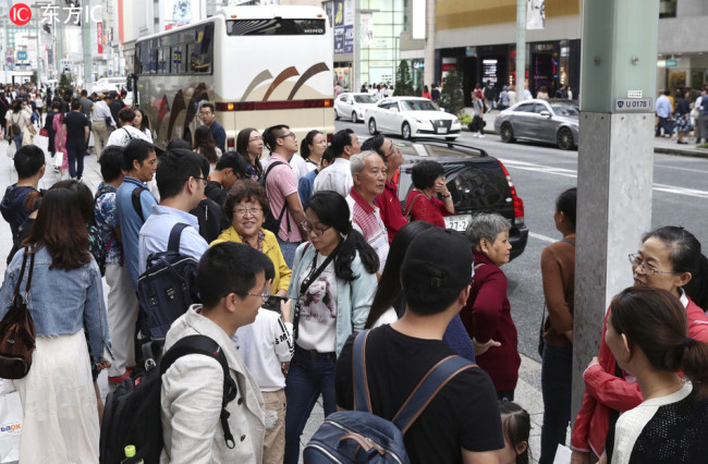 Chinese tourists waiting for their tour bus after enjoying shopping and sightseeing on the main street of the Ginza district, the most popular shopping area of Tokyo on October 3, 2018.[Photo:IC]