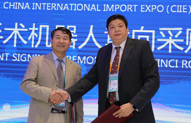 Beijing Hospital Vice President Xu Feng (L) shakes hands with Liu Yu, the senior vice president of Chindex Medical Limited, a supplier of the da Vinci family of surgical robots made by Intuitive, a company based in California. The pair had just signed a tentative sales agreement at the China International Import Expo in Shanghai on Tuesday, November 6, 2018 for a surgical robot system worth nearly 2.5 million U.S. dollars, along with a CT scanner and other equipment. [Photo: China Plus] 