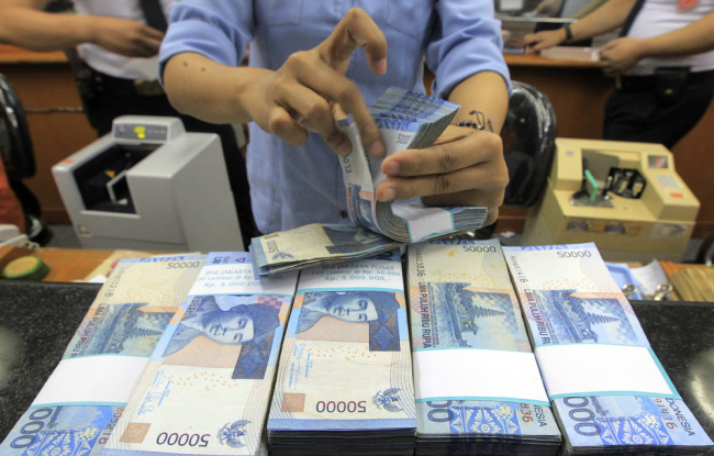 An Indonesian worker counts the Rupiah at a money changer in Jakarta, Indonesia, August 12, 2015. [File photo: IC]