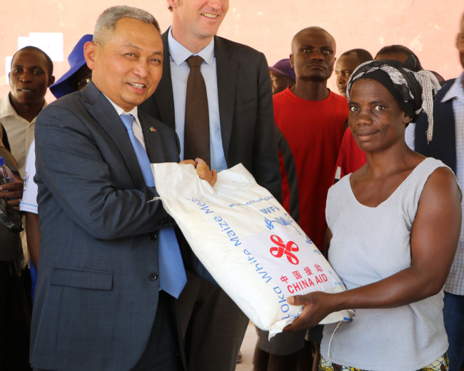 The Chinese Economic and Commercial Councilor in Zimbabwe Chen Ning (left) distributes food to a refugee in Zimbabwe’s Tongogara Refugee Camp on Tuesday, November 20, 2018. [Photo: China Plus/Gao Junya]