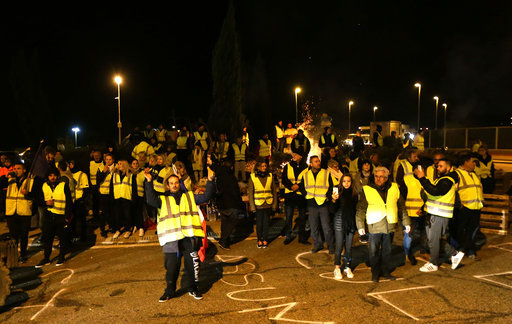 Protesters wearing yellow jackets block a crossroads in Saint-Maximin, southern France, Monday, Nov.19, 2018. The protests reflect broader frustration at President Emmanuel Macron, whose government is sticking to the fuel tax rise as part of efforts to clean up the environment. [Photo:AP]