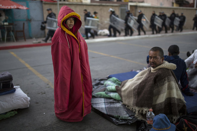 Jonathan Torres, 11, stands next to his father after waking up early in the morning as Mexican riot police make their way to the Chaparral border crossing, in Tijuana, Mexico, Friday, Nov. 23, 2018. [Photo: AP/Rodrigo Abd]