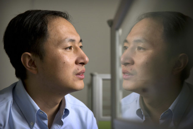 In this Oct. 10, 2018 photo, He Jiankui is reflected in a glass panel as he works at a computer at a laboratory in Shenzhen in southern China's Guangdong province. Chinese scientist He claims he helped make world's first genetically edited babies: twin girls whose DNA he said he altered. He revealed it Monday, Nov. 26, in Hong Kong to one of the organizers of an international conference on gene editing. [Photo: AP/Mark Schiefelbein]