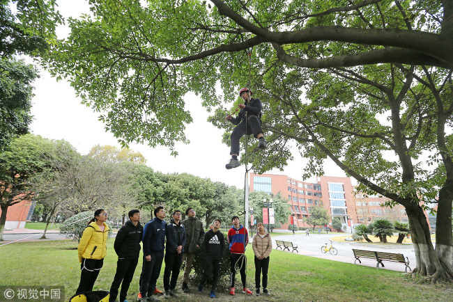 Li Zhonghua, the teacher of the tree-climbing course, shows students how to climb a tree properly during a class in Chengdu, the capital of Sichuan Province, on Friday, December 6, 2018. [Photo: VCG]