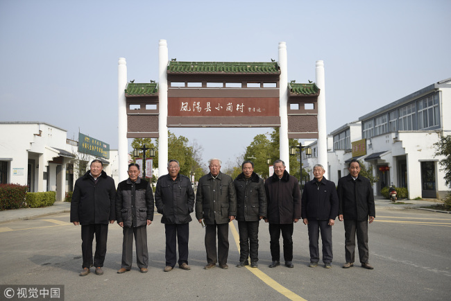The villagers who signed the pact in 1978 pose for a photo at the entrance to Xiaogang Village in 2008. [Photo: VCG]