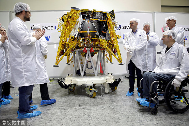 Members of Israeli non-profit group SpaceIL and representatives from Israel Aerospace Industries (IAI) stand next to an unmanned spacecraft during a presentation to the media of a time capsule, intended to travel to the moon with the spacecraft in early 2019, at the clean room of IAI's space division in Yehud, Israel December 17, 2018. [Photo: VCG/Amir Cohen]