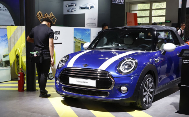 In this April 26, 2018, photo, cleaners wait near a MINI Cooper Cabrio displayed at the China Auto Show in Beijing. BMW Group and China's biggest SUV brand, Great Wall Motor, announced Tuesday, July 10, 2018, a partnership to produce electric MINI vehicles in China.[Photo: AP]