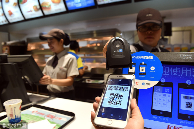 A cashier scans a QR code at a restaurant to receive payment. [File photo: VCG]