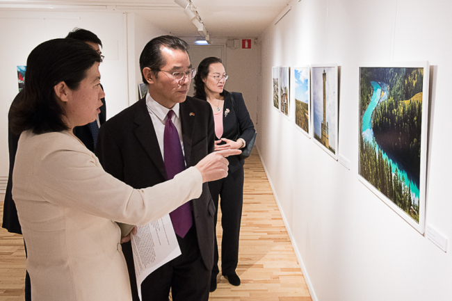 Xuefei Chen Axelsson, Editor of Green Post showed Mr. Gui Congyou, Chinese Ambassador to Sweden about Moon Bay Phot in Kanas region in Xinjiang Uyghur Autonomous Region.  [Photo: China Plus]