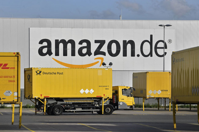 Post trucks leave the Amazon Logistic Center in Rheinberg, Germany on Nov. 14, 2018. [Photo: AP]