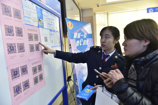 A tax officer explains new tax reduction policies to a taxpayer in Tianjin on December 26, 2018. [File photo: IC]