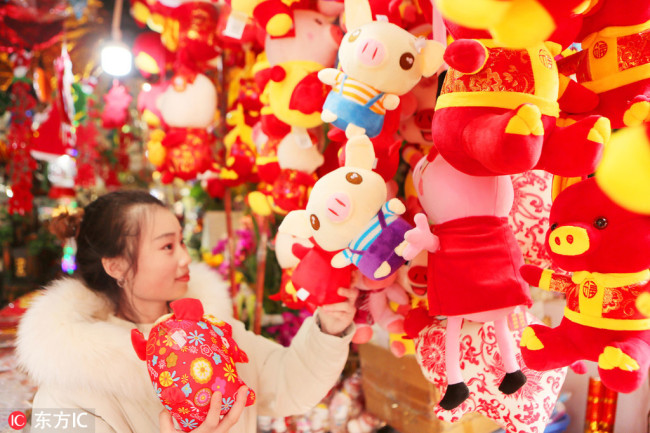 A customer picks(挑选 tiāoxuǎn) pig mascot at a store on Dec 17, 2018. [Photo/IC]