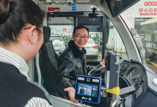The bus diver looks as a passenger scans her face to pay her fare onboard a bus in Jinhua, Zhejiang Province, January 7, 2019. [Photo: IC]