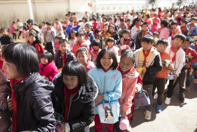 Students at Mingde Elementary School students in Jingwai, Yunnan Province queue up to receive a free meal on Sunday, January 6, 2019. [Photo: VCG] 
