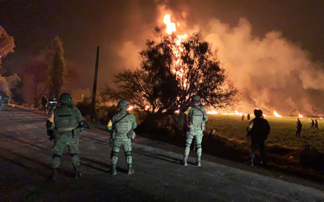 This handout photo distributed by the Mexican Secretary of National Defence (Secretaria de Defensa Nacional) shows Mexican soldiers standing guard near a fire after a leaking gas pipeline triggered a blaze in Tlahuelilpan, Hidalgo state, on January 18, 2019. [Photo: Handout / SECRETARIA DE DEFENSA NACIONAL / AFP]