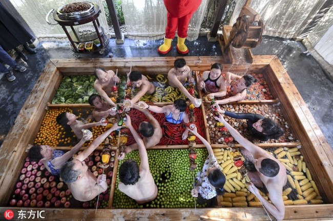 Visitors toast(干杯 gānbēi) in the nine-grid hotpot-shaped hot spring pool filled with vegetables and fruits at a hotel in Hangzhou, east China's Zhejiang Province, January 27, 2019. [Photo: IC]