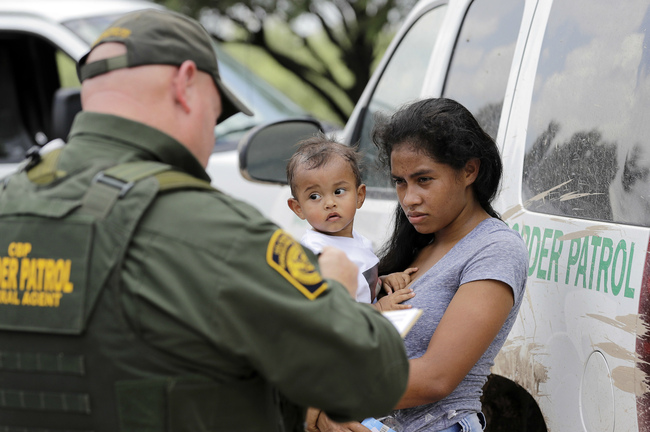 FILE - In this June 25, 2018, file photo, a mother migrating from Honduras holds her 1-year-old child as surrendering to U.S. Border Patrol agents after illegally crossing the border near McAllen, Texas. The Trump administration says it would require extraordinary effort to reunite what may be thousands of migrant children who have been separated from their parents and, even if it could, the children would likely be emotionally harmed. [Photo: AP/David J. Phillip]