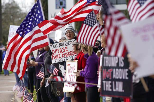 Alex McDonald of Houston, center, stands among protesters rallying along Memorial Drive outside the Houston office of Senator John Cornyn Monday, Feb. 18, 2019, in Houston. The event was part of nationwide protests against the national emergency declaration by President Donald Trump. [Photo: AP]