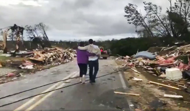 People walk amid debris in Lee County, Ala., after what appeared to be a tornado struck in the area Sunday, March 3, 2019. [Photo: AP]
