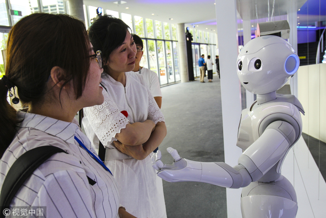 Visitors interact with a robot at the World Artificial Intelligence Conference in Shanghai on September 15, 2018. [Photo: VCG]