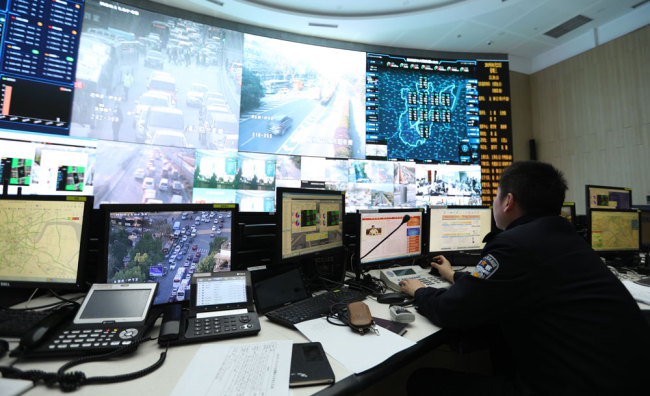 A policeman watches surveillance camera feeds of Hangzhou's transportation network at a control center in the city. [Photo: China Plus]