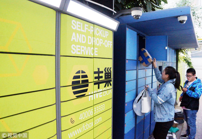 People pick up their parcels from self-service package lockers at a residential area in Changzhou, Jiangsu Province. [Photo: VCG]