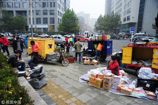 Deliverymen wait outside office buildings in Beijing for customers to pick up their parcels. [Photo: VCG]