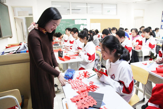 Yan Xiaoyan teaches a student paper-cutting during an elective class on the traditional art form at the High School Affiliated to Renmin University of China in Beijing on Thursday, March 7, 2019. [Photo: China Plus]