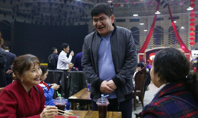 Imam Hasan is talking with the guests at Ancient City Food Plaza in Kashgar. [Photo:China Plus/ Du Junshuai]