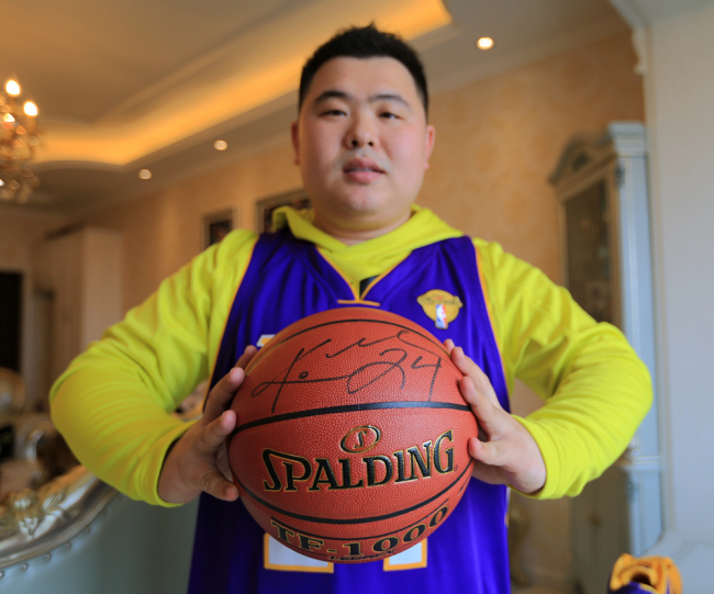 Liu Zhe, a fan of the retired NBA superstar Kobe Bryant, wearing a Los Angeles Lakers team jersey signed by Kobe at his home in Harbin, Heilongjiang Province on April 11, 2018. [File Photo: IC] 