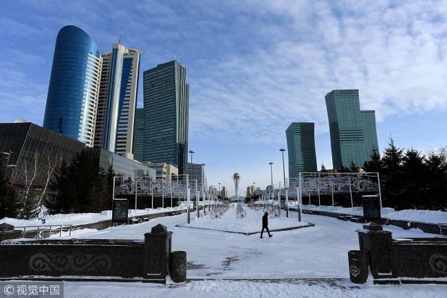In this file photo taken on January 22, 2017 a man walks in downtown Astana, with the Bayterek monument seen in the background. [File Photo: VCG]
