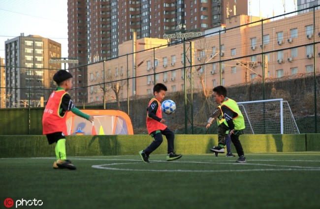 Three boys play football at a football school in Beijing, March 16, 2019. [Photo: IC]