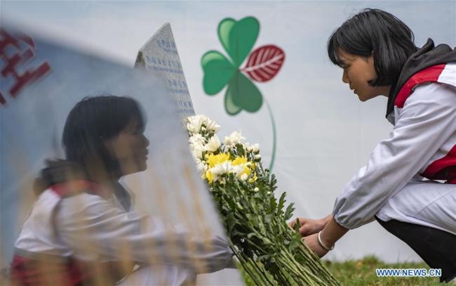 A volunteer lays flowers in front of a monument in honour of organ donors during a commemorative event held at a human organ donor memorial park in Kunming, southwest China's Yunnan Province, April 3, 2019. [Photo: Xinhua]