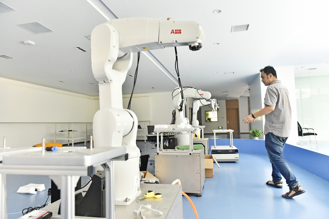 A technician stands besides robots at Zhejiang University's Binhai Industrial Technology Research Institute in Tianjin City on July 5, 2018. [File Photo: IC]