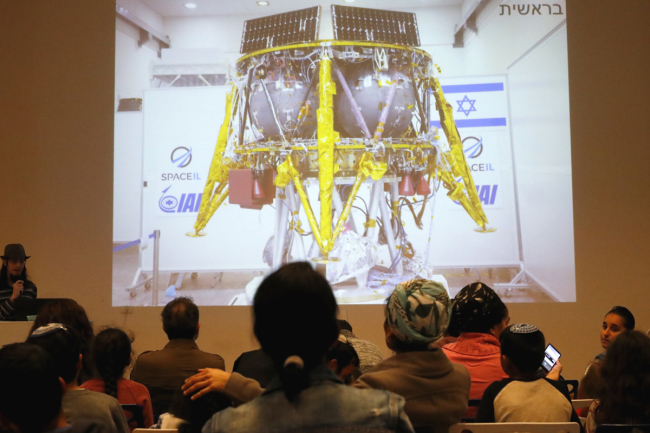 People watch a screen showing explanations of the landing of Israeli spacecraft, Beresheet's, at the Planetaya Planetarium in the Israeli city of Netanya, on April 11, 2019 before it crashed during the landing.[Photo: AFP/JACK GUEZ]  