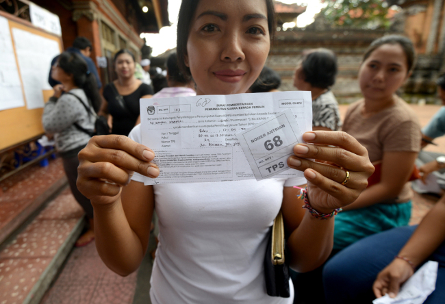 A woman shows her queueing number before casting her vote at a pooling center during the presidential election in Kuta on Indonesia's resort island of Bali on April 17, 2019. Indonesia kicked off one of the world's biggest one-day elections, pitting president Joko Widodo against ex-general Prabowo Subianto in a race to lead the Muslim-majority nation.[Photo: AFP/SONNY TUMBELAKA]