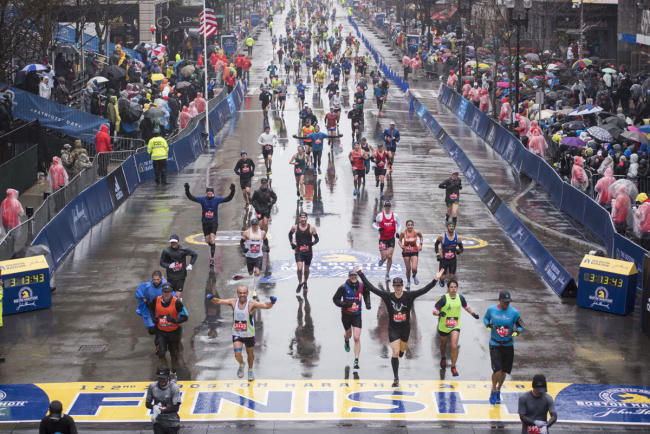 Runners come to the finish line of the 122nd Boston Marathon, where rain and high winds battered down for the duration. Monday April 16, 2018.[Photo: AFP/RYAN MCBRIDE] 