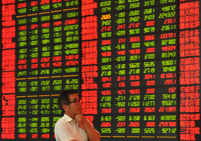 A Chinese investor looks at prices of shares (red for price rising and green for price falling) at a stock brokerage house in Fuyang city, east China's Anhui province.[File Photo: IC]