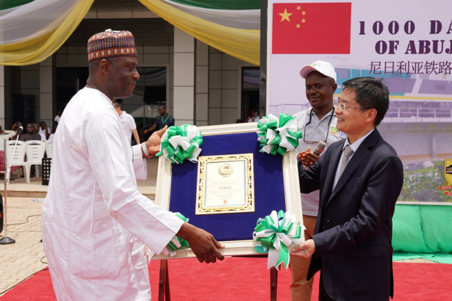 China Civil Engineering Nigeria manager Jiang Yigao (Right) receives the medal awarded by Nigeria Railway Corporation for safely running the Abuja-Kaduna railway since July, 2016. [Photo provided to China Plus]