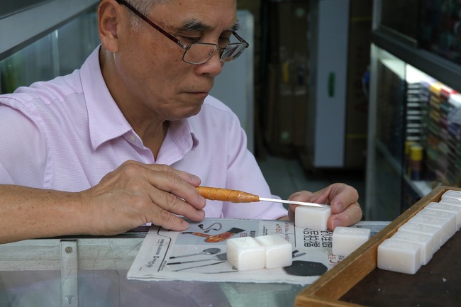 In this April 18, 2019, photo, Cheung Shun-king, 65-year-old maker of the popular table-top game mahjong tiles, engraves a character on a tile in his decades-old store 100 square feet downstairs shop in a Kowloon's old neighborhood of Hong Kong. [Photo: AP]