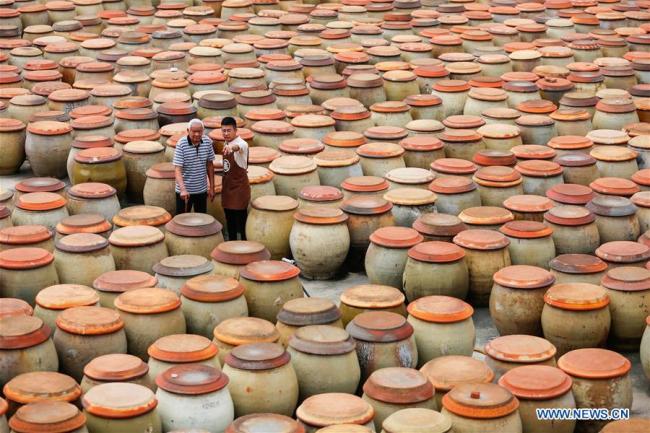 Wu Huaqing and his grandfather Wu Zongzhong patrol(巡查 xúnchá) among soy sauce jars at his company in Quanzhou, southeast China's Fujian Province, April 29, 2019. [Photo: Xinhua]
