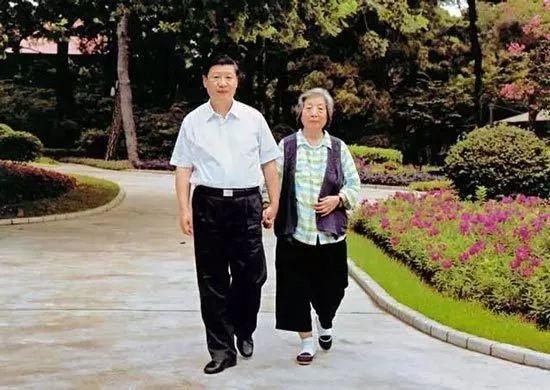 Undated photo on the book-shelf of President Xi Jinping shows him hand in hand with his mother, Qi Xin, walking in a park. [Photo: China Plus]