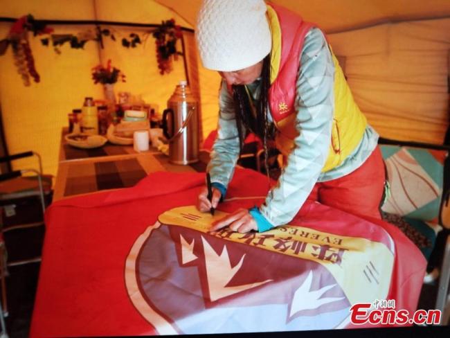 The mountaineer from Xinjiang Uygur Autonomous Region signs a banner before climbing Mount Qomolangma, known as Mount Everest in the West, on May 22, 2019. [Photo: China News Service]<br/><br/>