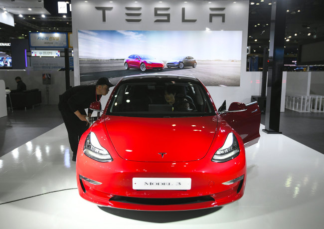 Visitors look at a Tesla Model 3 during a press preview of the Seoul Motor Show in Goyang, northwest of Seoul, on March 28, 2019. [File photo: AFP/ JUNG Yeon-Je] 