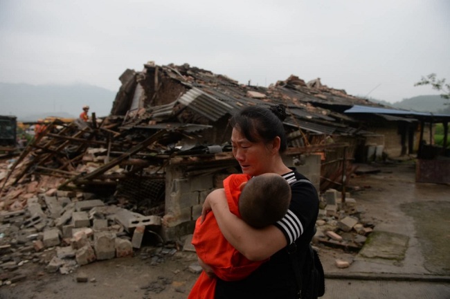 A Chinese woman weeps as she holds her child in her arms in the debris of residential buildings damaged by the 6.0-magnitude earthquake in Changning county, Yibin city, southwest China's Sichuan province, 18 June 2019. [Photo: IC]