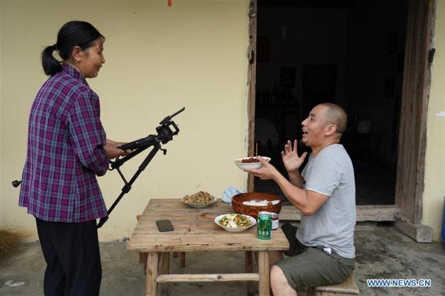 Jiang Jinchun (R) and his mother have a live eating broadcast in Zaotian Village in Hengfeng County, east China's Jiangxi Province, June 19, 2019. [Photo: Xinhua]